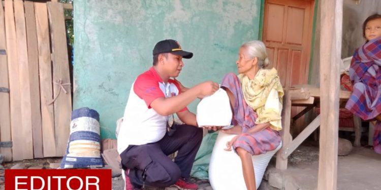 IPDA Muh. Sofyan Hidayat sedang menyerahkan bantuan kepada nenek tua renta salah satu korban banjir Bima. (foto : SOFYAN).